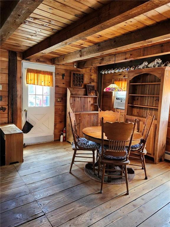 dining area featuring wooden ceiling, beamed ceiling, wood walls, cooling unit, and light hardwood / wood-style floors