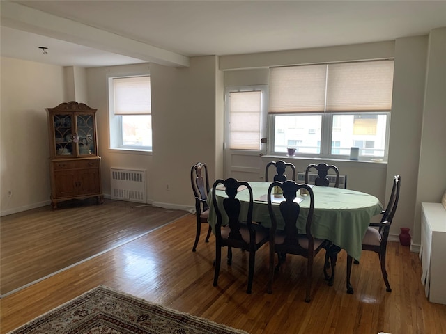 dining space with wood-type flooring and radiator heating unit