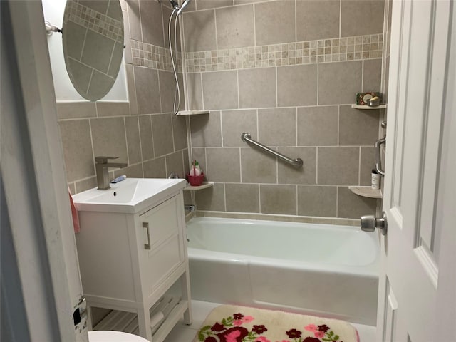 full bathroom featuring vanity, toilet, tiled shower / bath, and tile walls