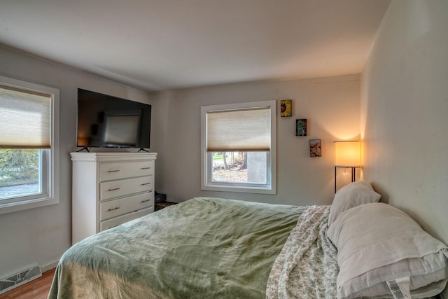 bedroom with light hardwood / wood-style floors and multiple windows