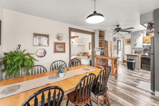 dining room featuring a wall unit AC, ceiling fan, and light hardwood / wood-style flooring