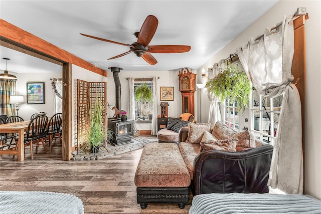 living room with a wood stove, ceiling fan, and hardwood / wood-style floors