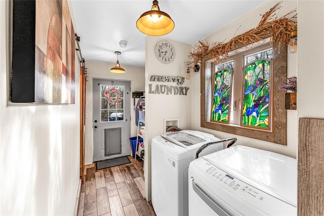 laundry area featuring wood-type flooring, washing machine and dryer, and a barn door