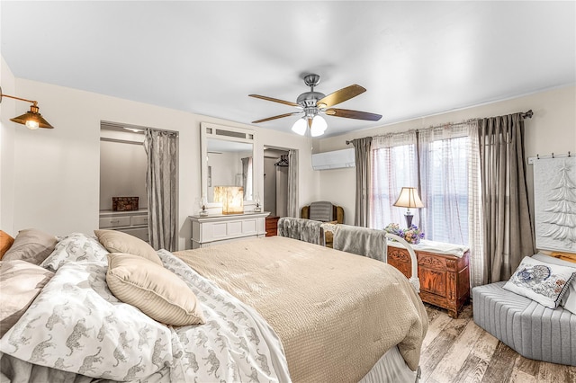 bedroom with ceiling fan, light wood-type flooring, and an AC wall unit