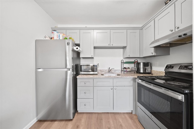 kitchen with light stone counters, sink, stainless steel appliances, and light wood-type flooring