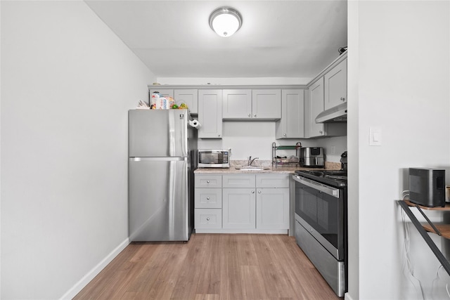 kitchen with appliances with stainless steel finishes, light hardwood / wood-style floors, and sink