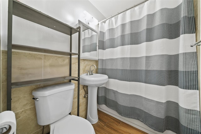 bathroom featuring a shower with shower curtain, hardwood / wood-style floors, toilet, and tile walls