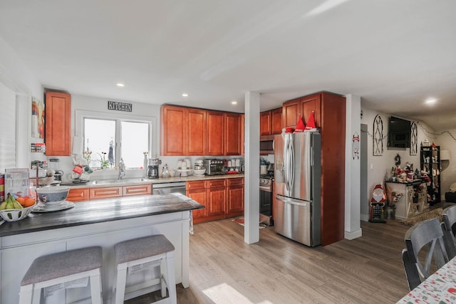 kitchen featuring a kitchen bar, stainless steel appliances, light hardwood / wood-style flooring, and sink