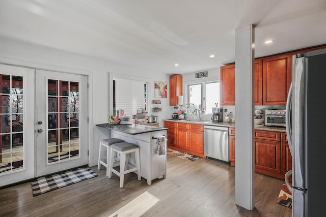 kitchen with a breakfast bar, french doors, sink, appliances with stainless steel finishes, and light hardwood / wood-style floors