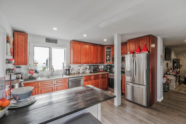 kitchen featuring light stone countertops, appliances with stainless steel finishes, light wood-type flooring, and sink