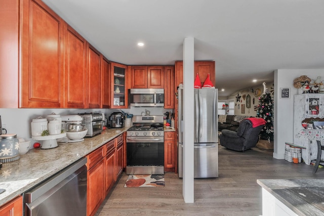 kitchen with light stone countertops, stainless steel appliances, and wood-type flooring