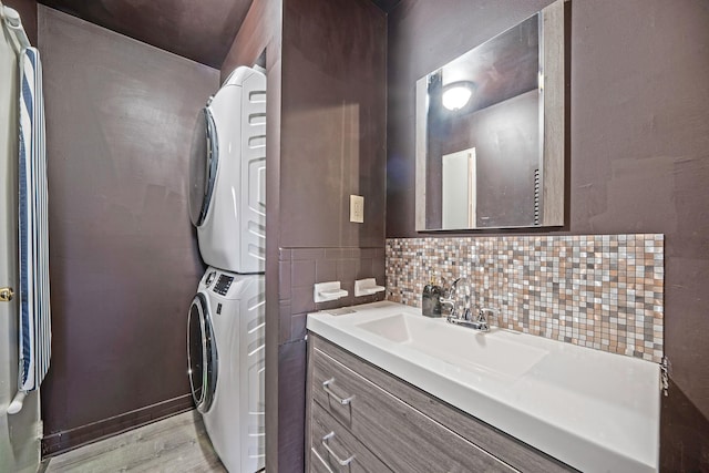 laundry area with light hardwood / wood-style floors, stacked washer and clothes dryer, and sink