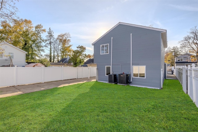 rear view of house with a lawn and central AC