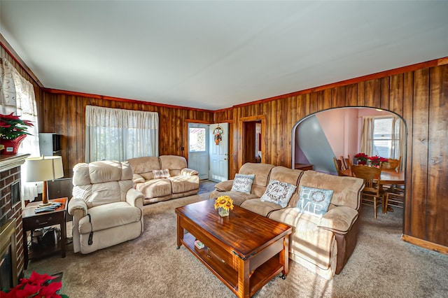 living room with a wealth of natural light, crown molding, and wood walls