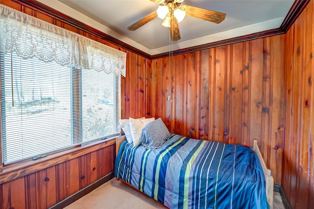 bedroom with light carpet, ceiling fan, and wooden walls