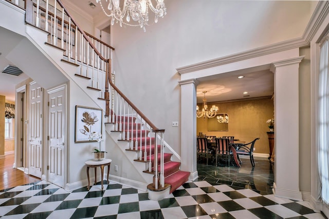 stairs featuring decorative columns, ornamental molding, and an inviting chandelier