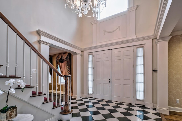 foyer featuring crown molding, a high ceiling, and an inviting chandelier