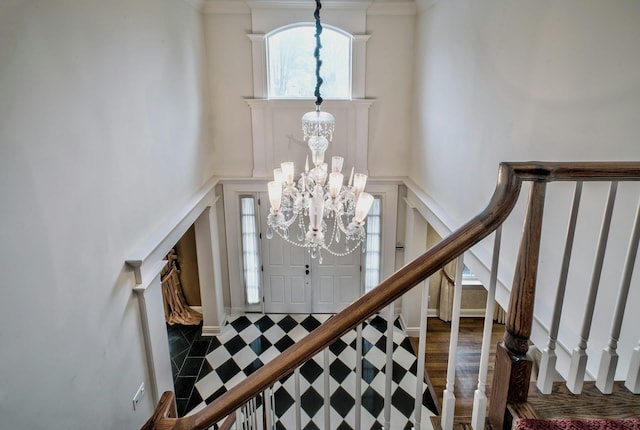 foyer entrance featuring dark hardwood / wood-style flooring, crown molding, and a chandelier