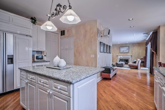 kitchen with light wood-type flooring, decorative light fixtures, and a kitchen island