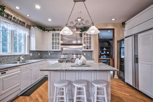 kitchen with dishwasher, a breakfast bar, decorative light fixtures, and a kitchen island