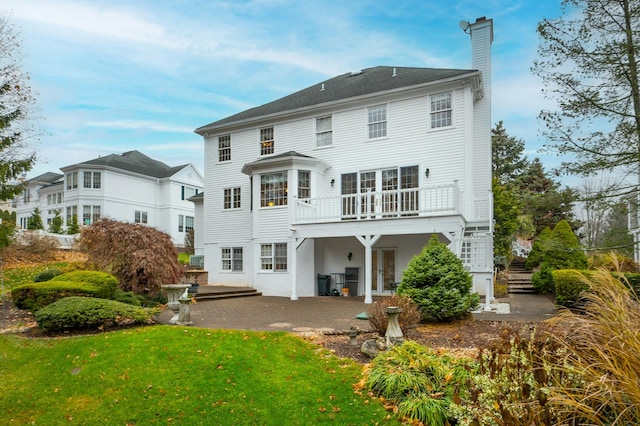 rear view of property featuring a lawn, a patio area, and a balcony