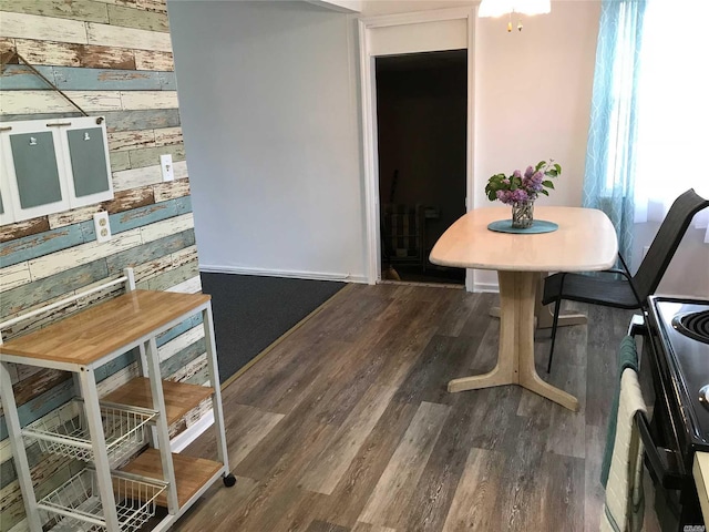 dining space featuring a healthy amount of sunlight, wood walls, and dark wood-type flooring