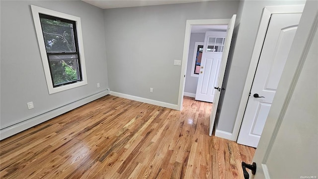 unfurnished bedroom with a baseboard heating unit and light hardwood / wood-style flooring