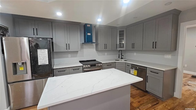 kitchen featuring a center island, dark wood-type flooring, wall chimney range hood, sink, and appliances with stainless steel finishes