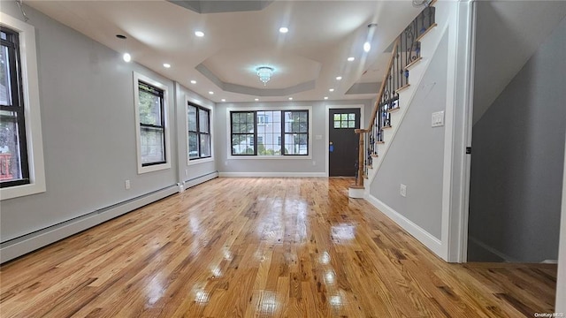 entrance foyer with a baseboard heating unit, a raised ceiling, and light hardwood / wood-style flooring