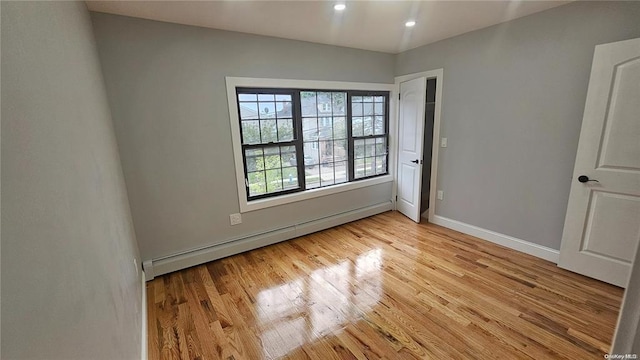 unfurnished room featuring light hardwood / wood-style floors and a baseboard radiator