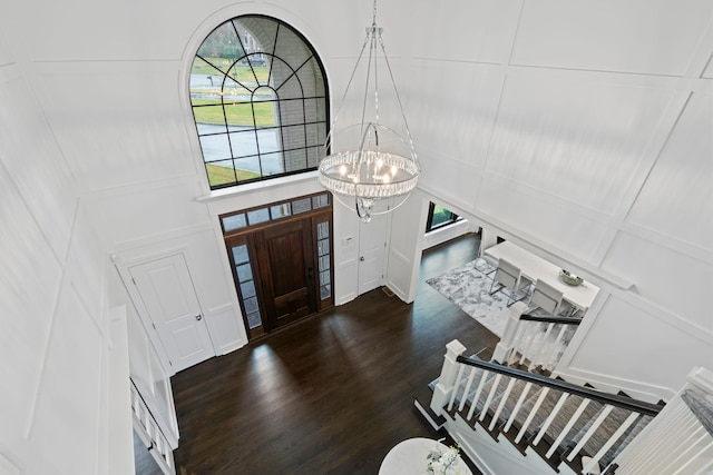 entrance foyer with dark hardwood / wood-style flooring, a towering ceiling, and a chandelier