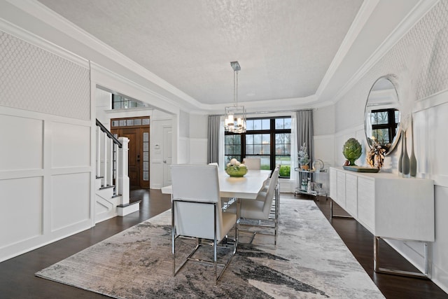 dining space featuring an inviting chandelier, a tray ceiling, crown molding, dark wood-type flooring, and a textured ceiling