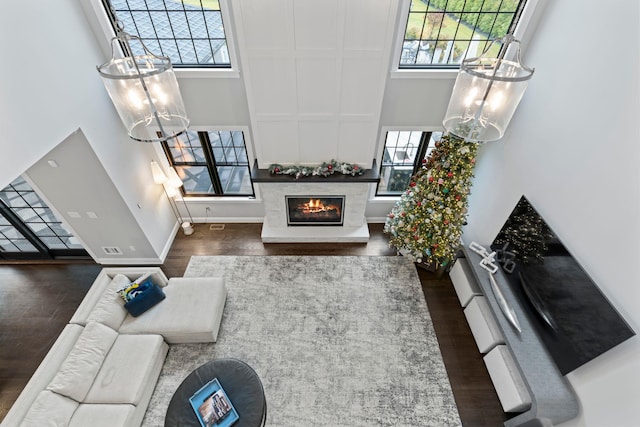 living room with dark hardwood / wood-style flooring, a towering ceiling, and a healthy amount of sunlight