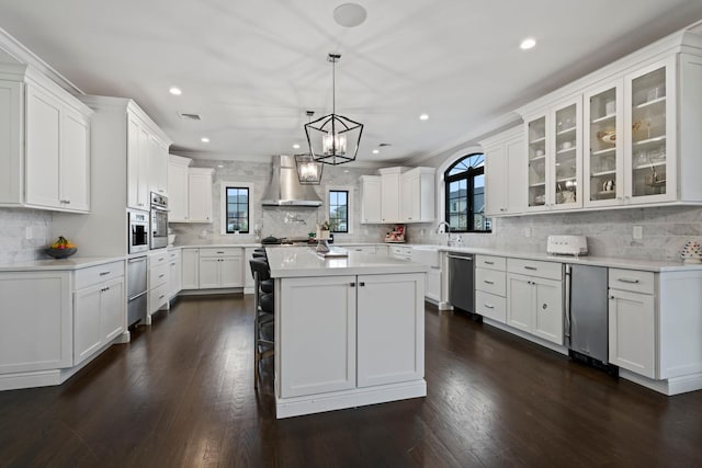 kitchen with white cabinets, wall chimney exhaust hood, and appliances with stainless steel finishes