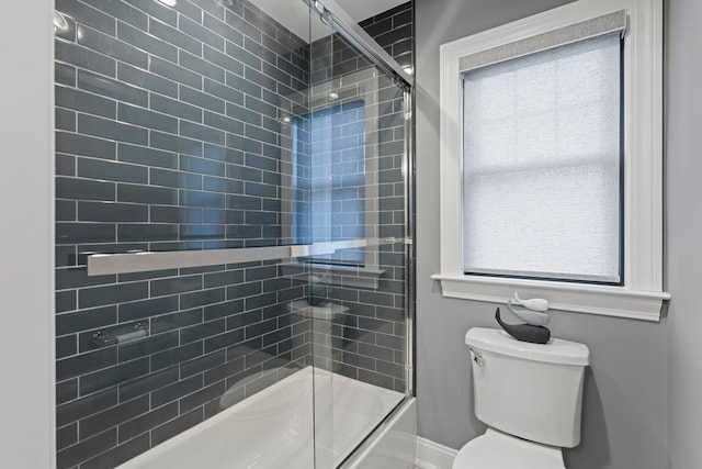 bathroom featuring a wealth of natural light, shower / bath combination with glass door, and toilet