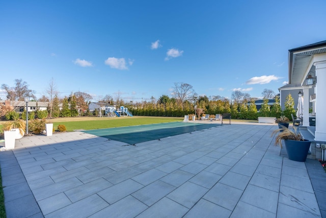 view of swimming pool featuring a yard, a patio area, and a playground