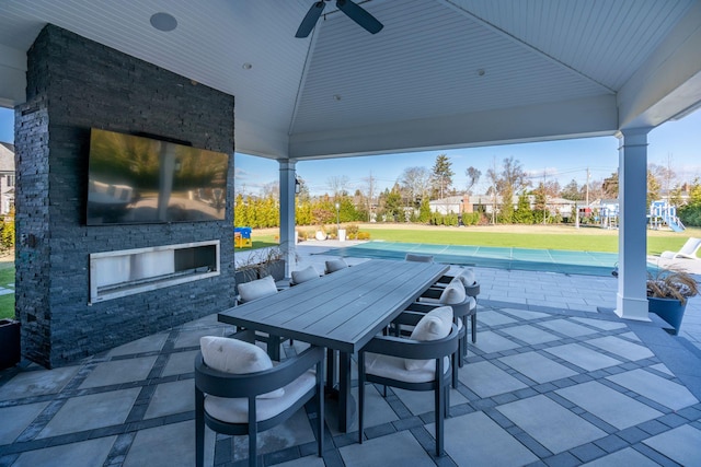 view of patio with a gazebo, ceiling fan, a playground, and an outdoor stone fireplace