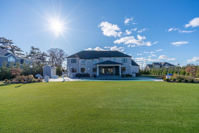 rear view of property with a storage shed, a patio, and a lawn