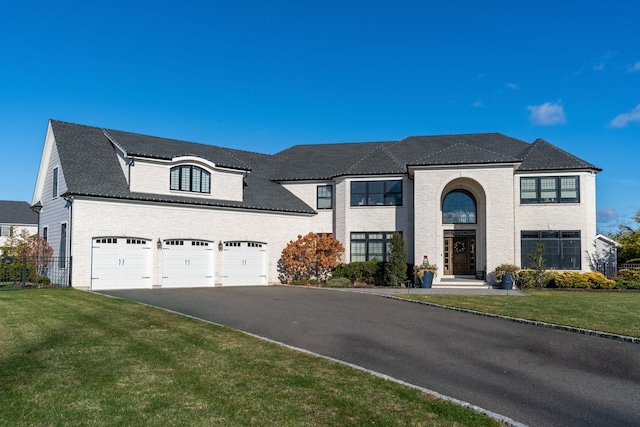 french country inspired facade featuring a garage and a front lawn