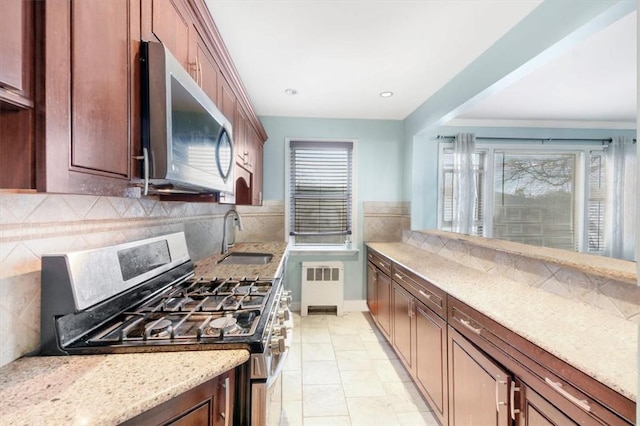 2 Soundview Ave Unit 2D, White Plains, NY 10606 - kitchen featuring appliances with stainless steel finishes, radiator heating unit, decorative backsplash, and light stone countertops