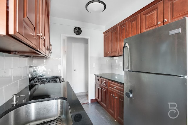 kitchen featuring refrigerator, sink, backsplash, stove, and tile patterned floors