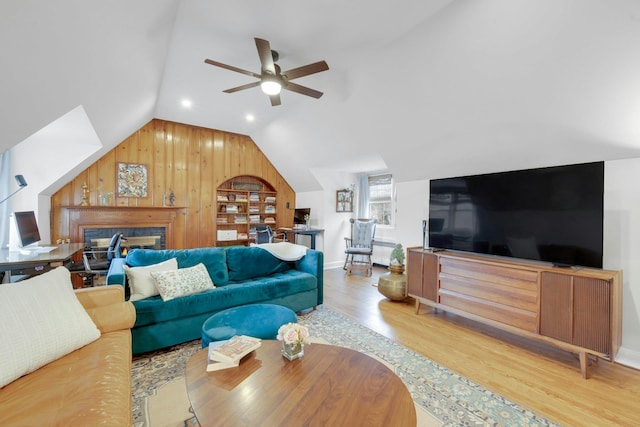 living room with ceiling fan, light wood-type flooring, and lofted ceiling