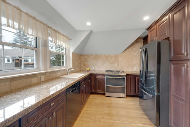 kitchen with sink, vaulted ceiling, light hardwood / wood-style flooring, decorative backsplash, and stainless steel appliances