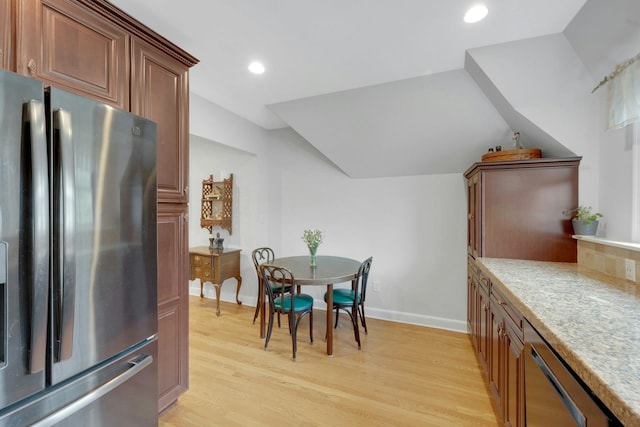 dining space with vaulted ceiling and light hardwood / wood-style flooring