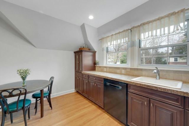 kitchen with light wood-type flooring, dark brown cabinets, black dishwasher, and sink