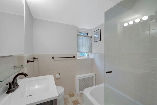 bathroom featuring radiator, a washtub, vanity, tile walls, and toilet