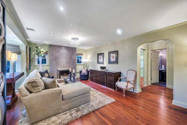 living room with a fireplace, dark wood-type flooring, and a chandelier