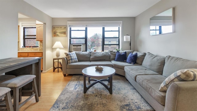 living room featuring plenty of natural light, cooling unit, and light wood-type flooring