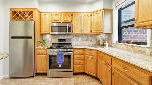 kitchen with a wealth of natural light, decorative backsplash, sink, and appliances with stainless steel finishes