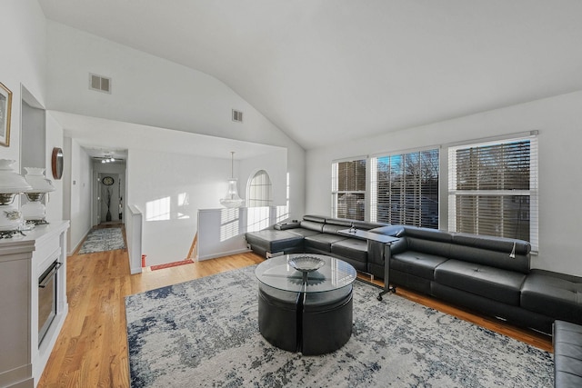 living room with light hardwood / wood-style floors, high vaulted ceiling, ceiling fan, and a healthy amount of sunlight